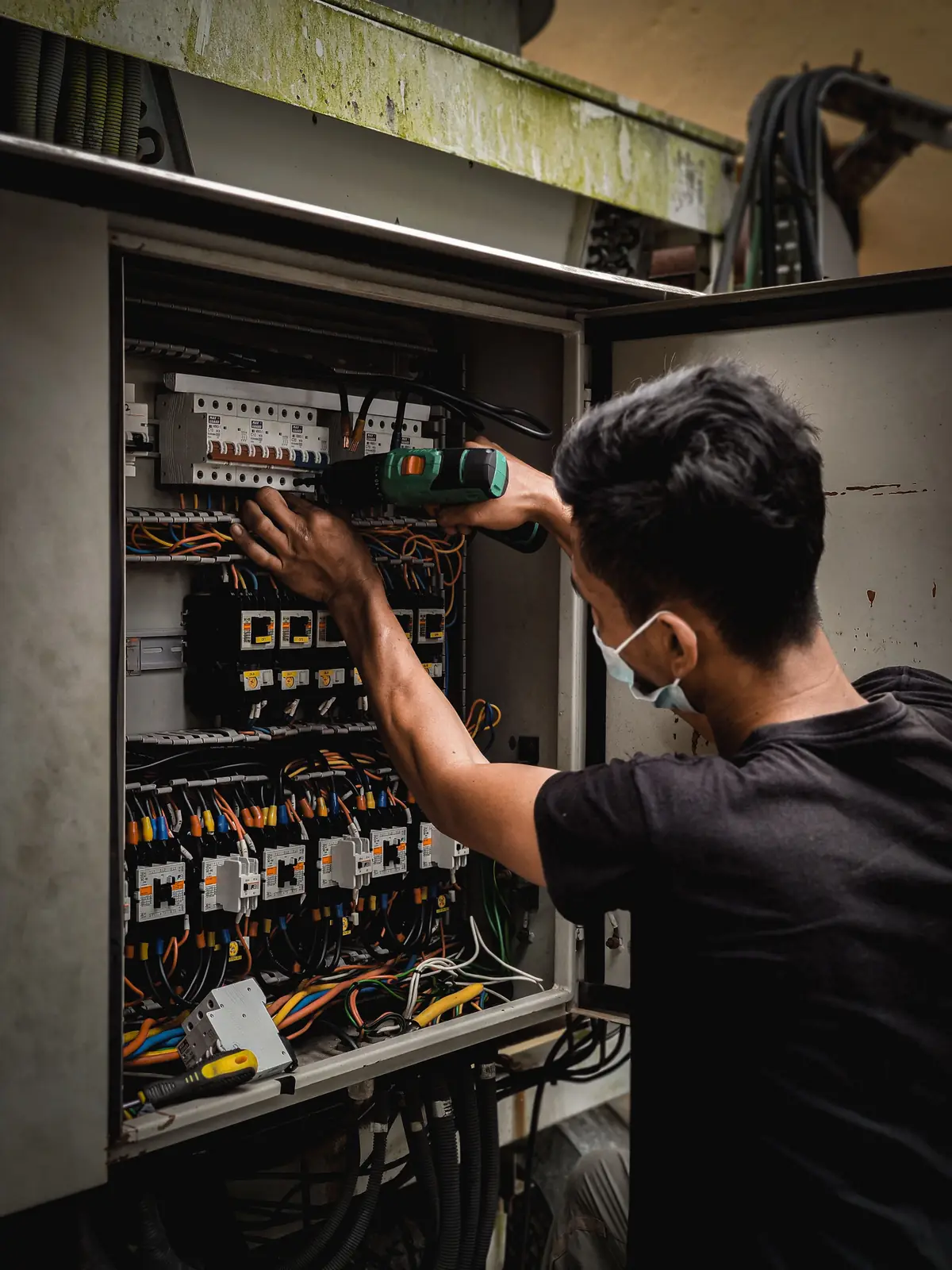 An electrician working inside a large distribution board, for commercial electrical in Hamilton